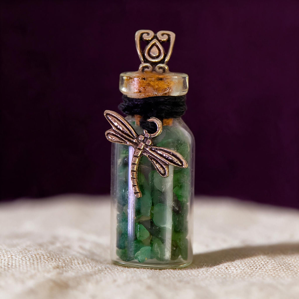 glass bottle of aventurine chips with dragonfly charm